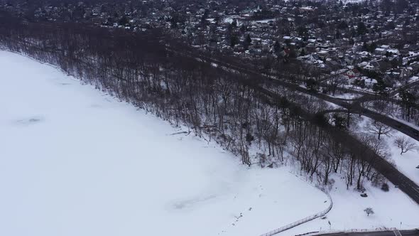 An aerial view from a drone, over a frozen lake during a cloudy sunrise. The drone camera truck righ