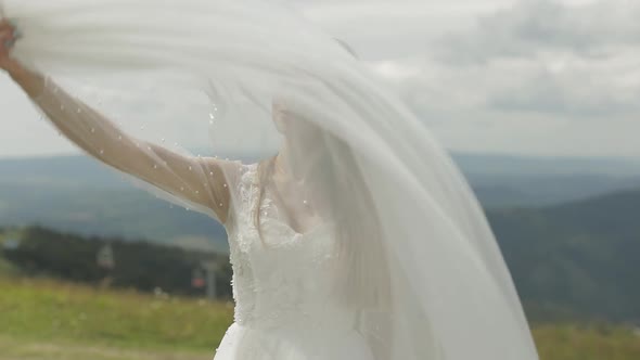 Beautiful Bride in Wedding Dress and Veil on the Mountains. Slow Motion