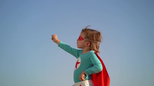 Superhero child against blue sky background alt