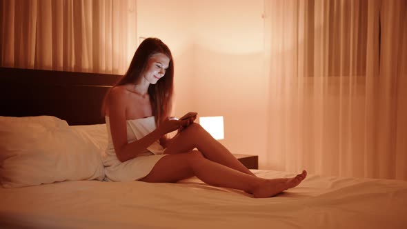 Woman Use of Mobile Phone and Sit on Bed at Night