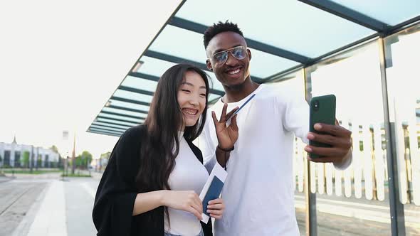 Two Friends Greeting Joint Mate with Waving Hands During Video Chat on Mobile Outdoors