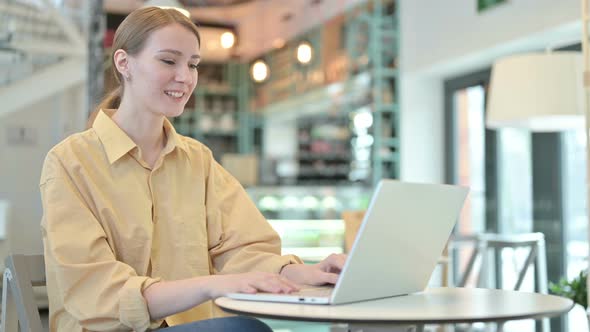 Video Chat on Laptop By Young Woman in Cafe 