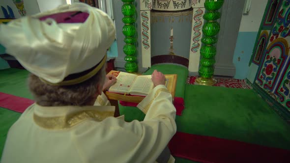 Muslim Mosque Teacher is reading the Quran in Small Historic Wooden Masjid