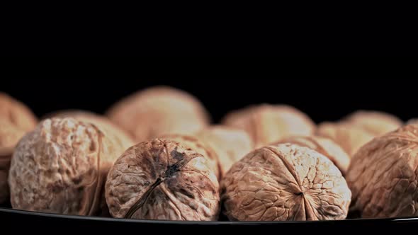 Lot of Walnuts in the Shell are Spinning on a Black Background