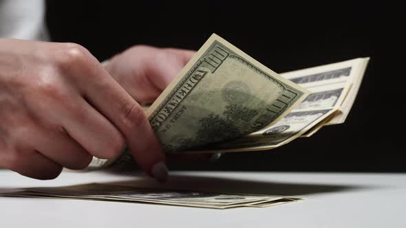 Counting American Hundred Dollar Banknotes on Black Background