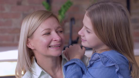 Happy Motherhood, Little Smiling Child Girl Tells Beloved Mum Whispering Secrets in Ear at Home