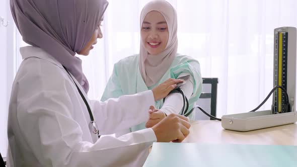 Doctor measuring blood pressure of young woman in clinic