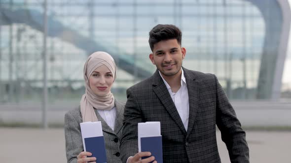 Muslim Couple Posing on Camera Outside Airport Demonstrating Their Passports and Tickets