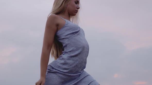 A Young Blonde Female Gracefully Dances Under a Sky of Gray Shade