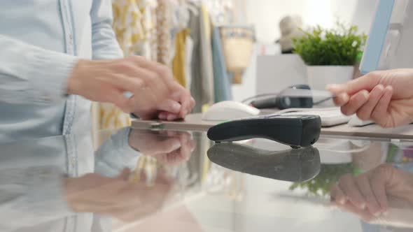 Closeup of Salesman's Hands Accepting Smartphone Payment Then Using Computer in Modern Shop