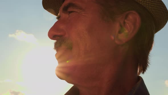 Close Up of a Human Head Aged Farmer with Mustache Against in the Sky Background