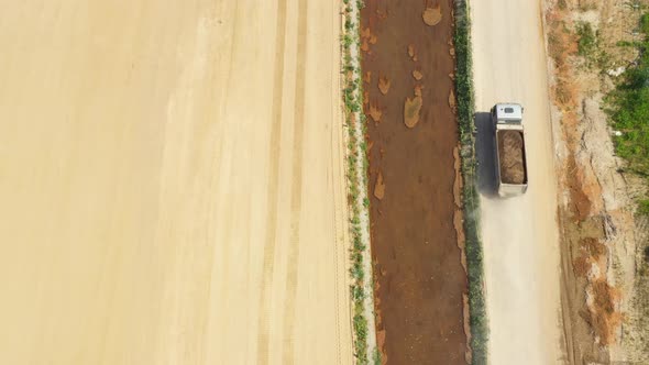 Dumper truck with sand is going, passing over highway construction side. Aerial View