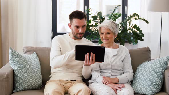 Old Mother and Adult Son with Tablet Pc at Home