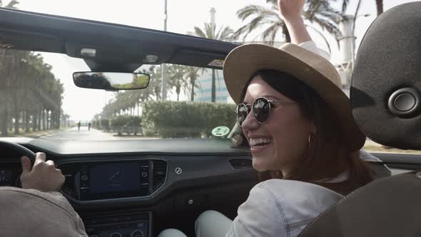 Happy Young Couple Laughing Together While Driving a Convertible Car on Holidays