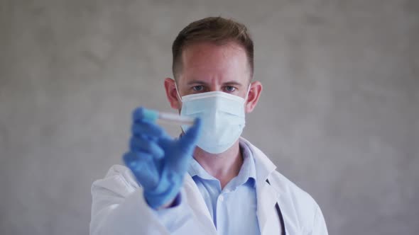 Caucasian male doctor wearing face mask and holding vaccine