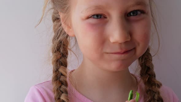 Little girl with fresh spinach in hand white background. Child eats natural raw clean food