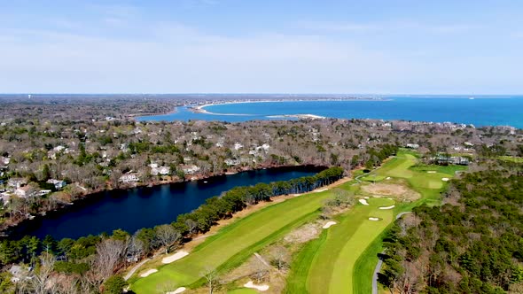 Massive green and vibrant golf field near luxury town of Osterville and Atlantic ocean, aerial view