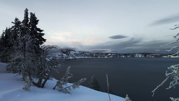 Aerial video of snowy shore of Crater Lake, Oregon, USA, drone footage of lake