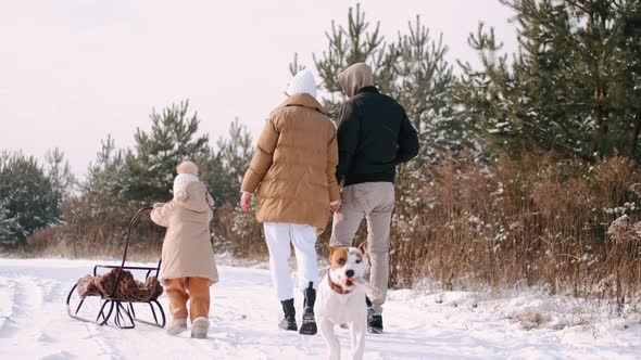 Young Family Walking Near Forest in Countryside in Winter