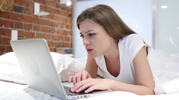 Woman in Bed Working on Laptop and Reacting to Loss Failure