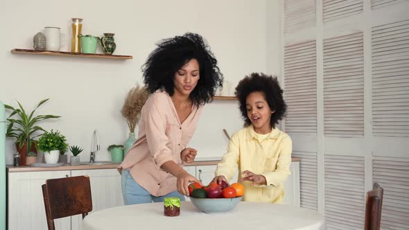 African American Woman and Girl Dancing Merrily Throwing a Red Apple to Each Other and Hugging