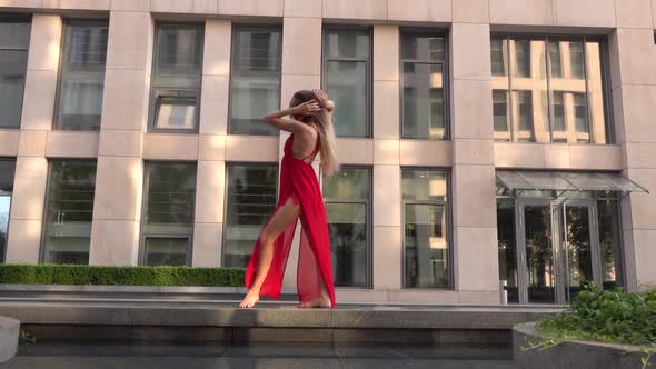 Beautiful Young Girl Dancing on the Street of a Modern City and Is Reflected in the Water. She Is