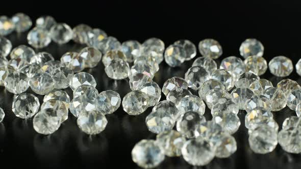 White beads for making jewelry on a black surface and rotating. Iridescent stones for jewelry