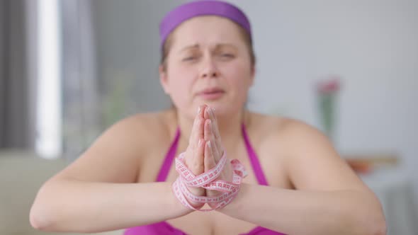 Rack Focus From Hand Tied with Measuring Tape to Young Plussize Depressed Woman Looking at Camera