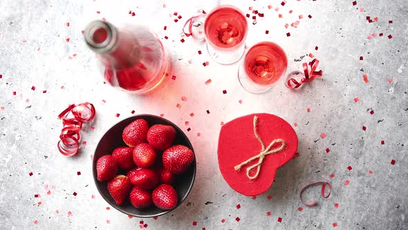 Bottle of Rose Champagne, Glasses with Fresh Strawberries and Heart Shaped Gift