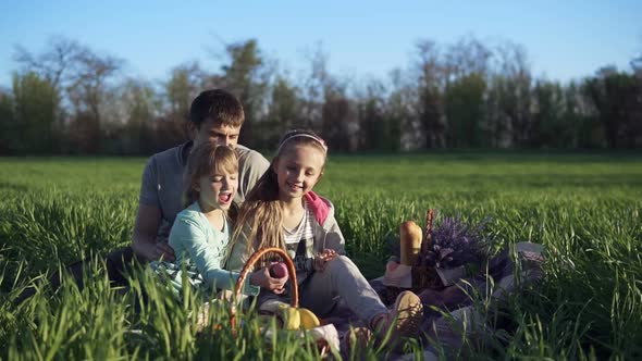 Happy Family Father and Daughters are Sitting Close Together and Enjoy the Time at the Picnic on the