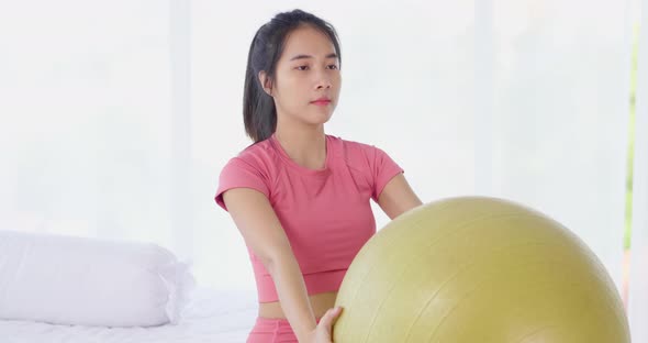 Asian woman arm muscle workout with yoga ball for weight training and yoga exercise at home