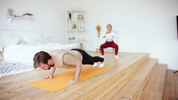 Young Couple is Doing Pushups and Squats Excercises at Home in Cozy Bright Bedroom