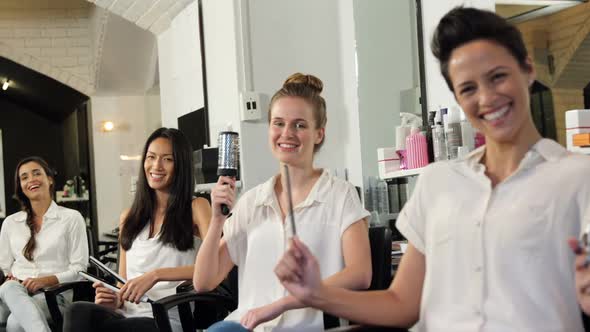 Smiling hairdressers sitting on chair in salon