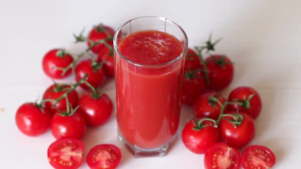 Glass with Tomato Juice on a White Background, a Drop of Juice Falls Into Glass