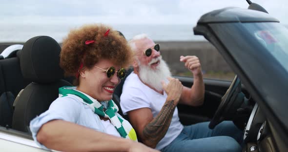 Senior couple inside a convertible car on holiday time
