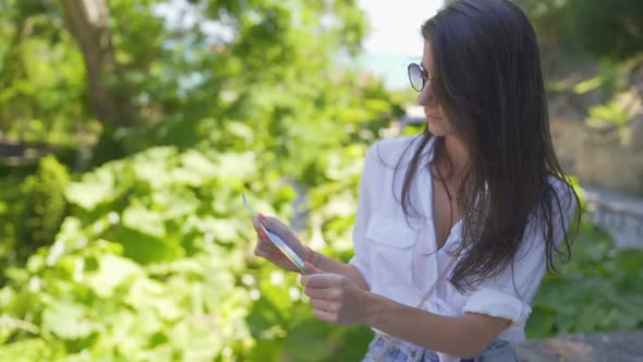 Pretty Tourist Girl with White Shirt and Sunglasses Holding Tourist Map and Checking the Way