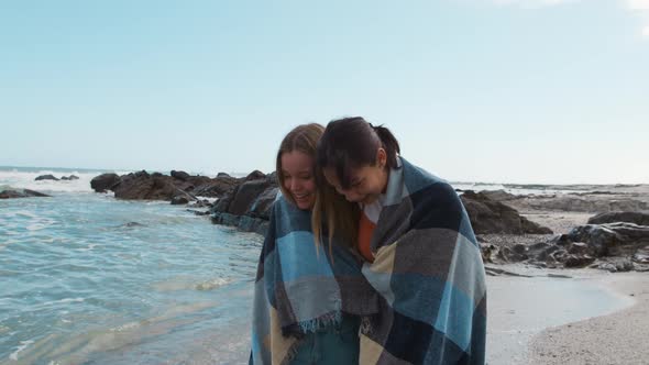 Front view of a Caucasian and a mixed race girl walking by the sea