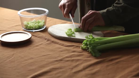 vegetarian man cuts Celery on a chalkboard in the kitchen with a knife