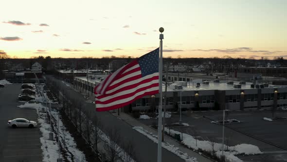 Orbiting an American flag waving in the wind at sunset - parallax aerial view