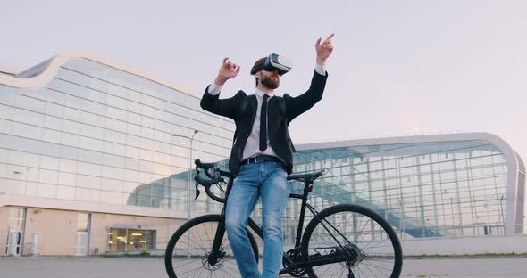 Businessman Standing Near His Bike in Virtual Reality Headset and Working on Imaginary Screen