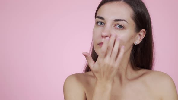 Portrait of Beautiful Woman Applying Face Cream Isolated on Pink Background