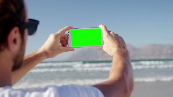 Man taking photo with mobile phone at beach