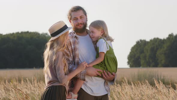 Happy Caucasian Family Farmers Young Parents with Little Daughter Girl Child Stand Outdoors in Wheat