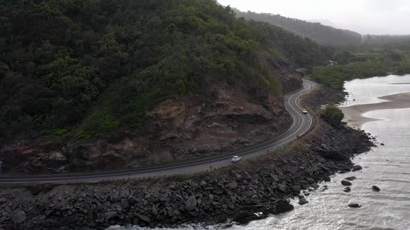 Captain Cook Highway aerial with white car and rocky coast, Far North Queensland, Australia