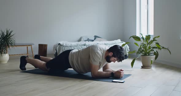 Strong Bearded Guy Doing Plank Exercise, Using Stopwatch