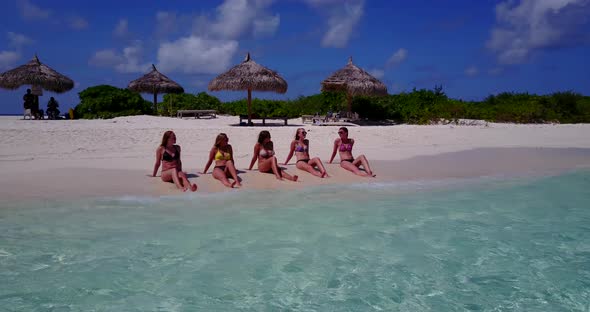 Pretty smiling ladies relaxing having fun on the beach on summer white sand and blue 4K background