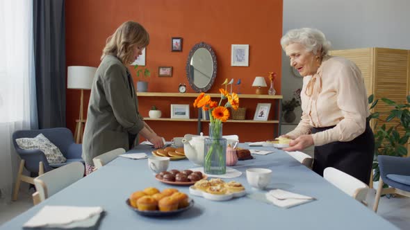 Young Woman Helping Grandma with Setting Festive Dinner Table