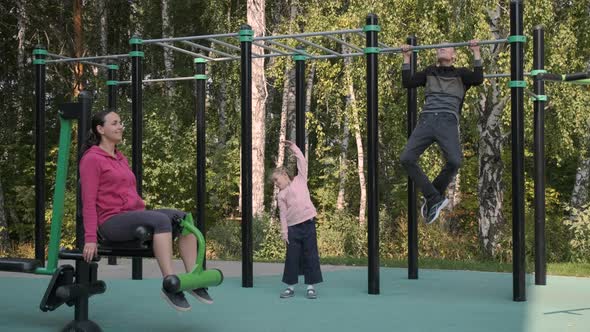 Family of Three Exercising in an Outdoors Gym