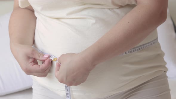 pregnant woman sitting on bed measuring big belly female advanced pregnancy last trimester