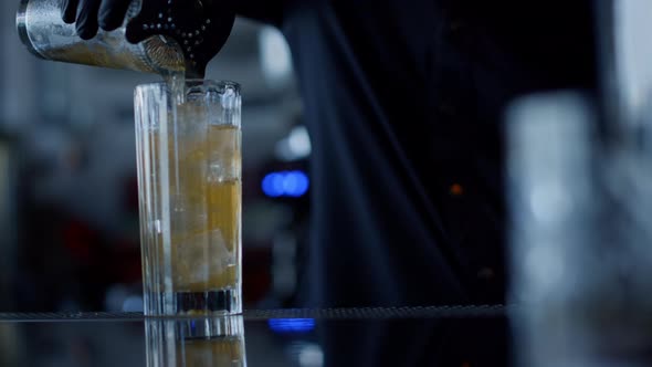 Closeup Bartender Hands Pouring Cocktail in Glass